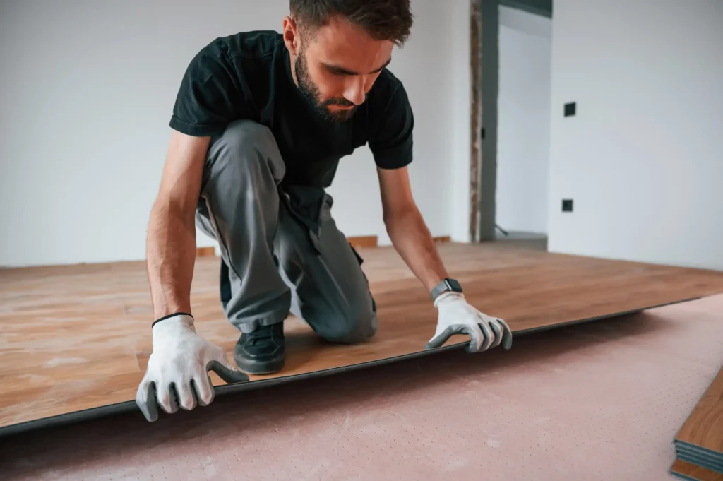A man carefully placing the new laminated wooden floor.